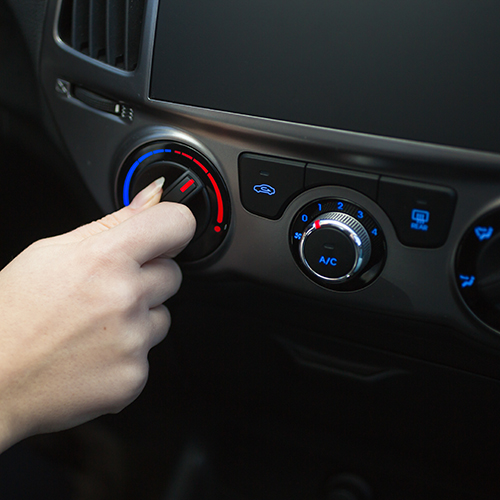 Female driver turning car air conditioner knob